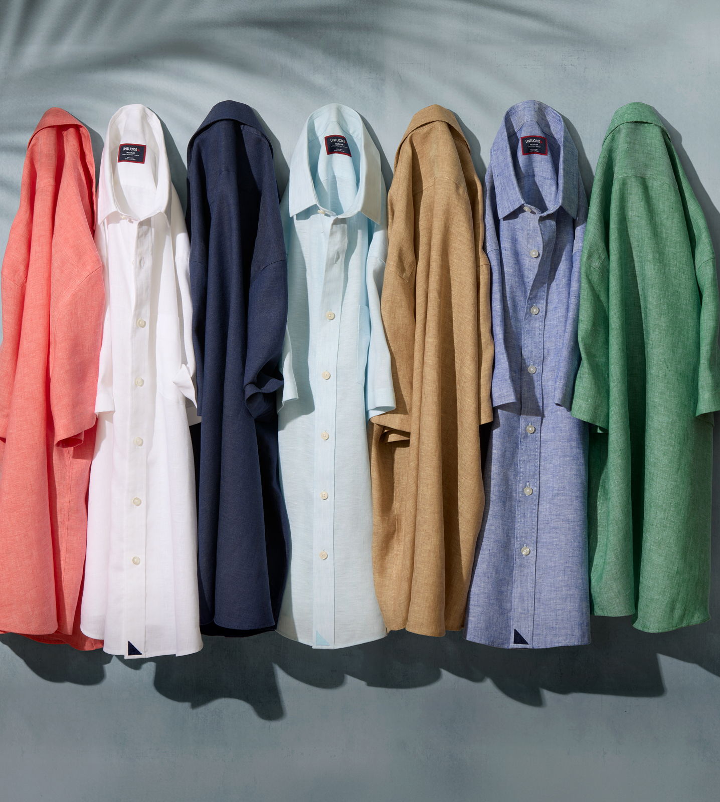 A row of colorful shirts hanging against a neutral background.