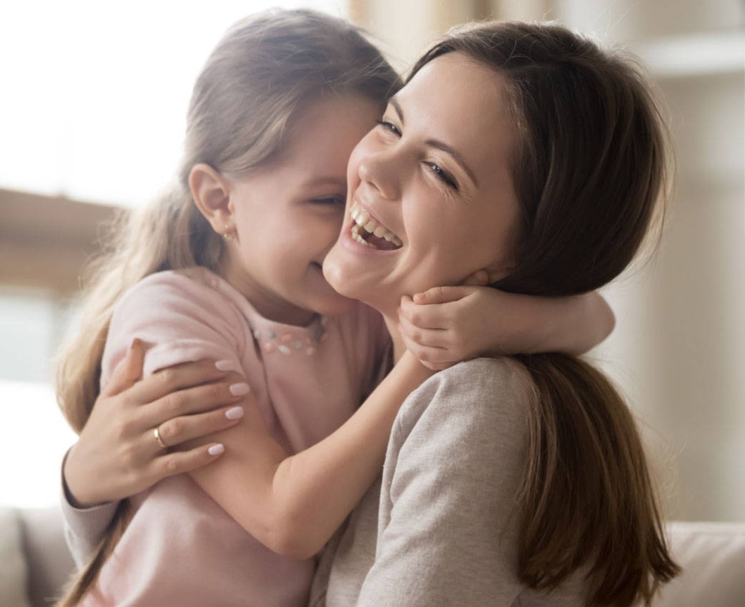 a smiling mother and daughter hug