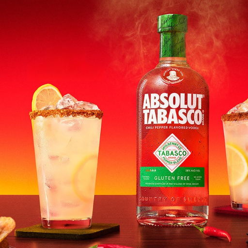 Bottle of Absolut Tabasco with cocktails and chili peppers on a colorful background.