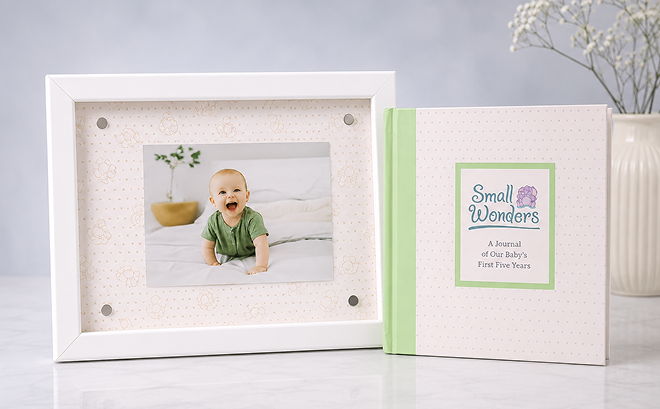 A framed photo of a baby next to a keepsake book.
