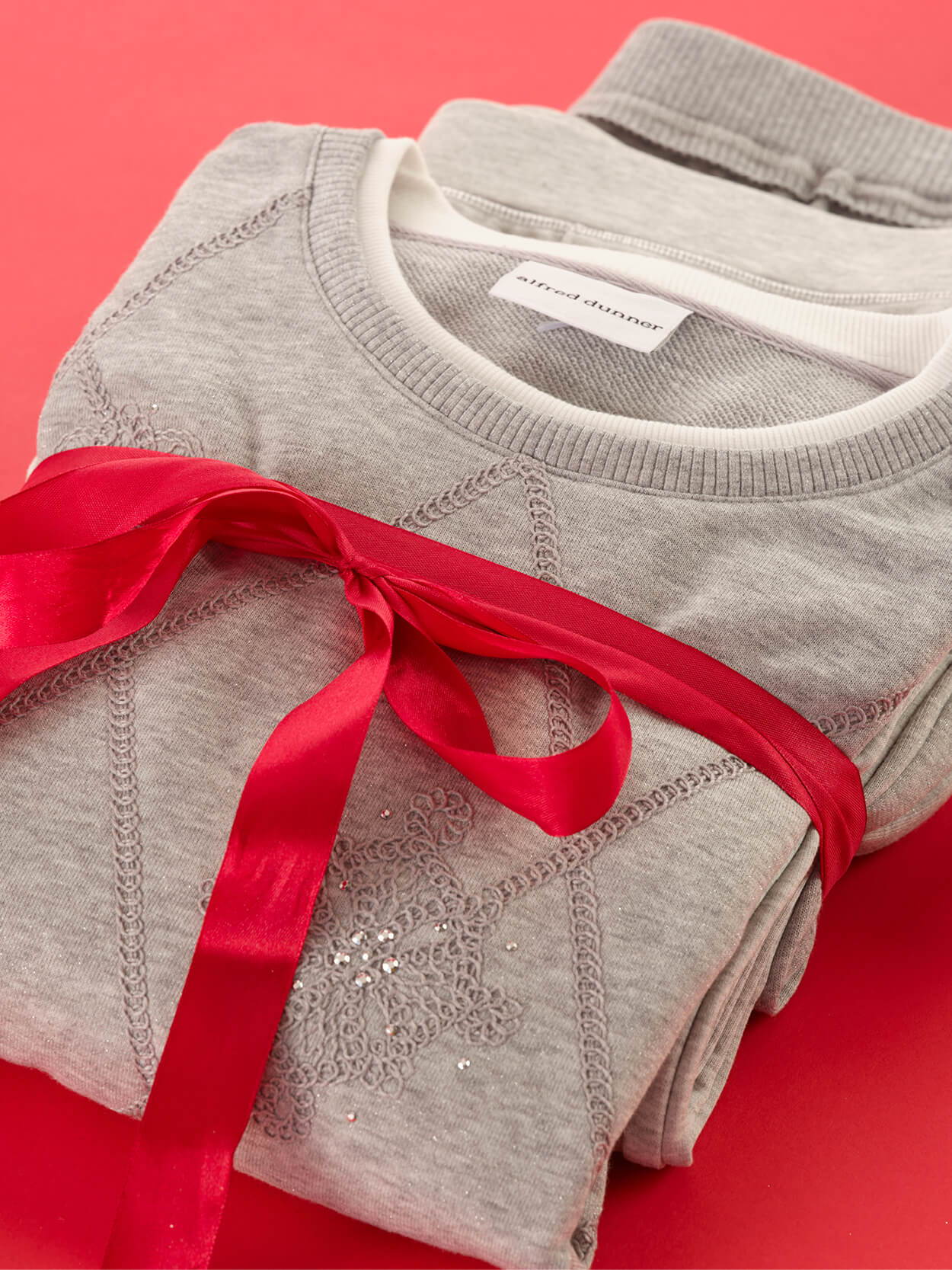 A stack of folded gray sweatshirts tied with a red ribbon.