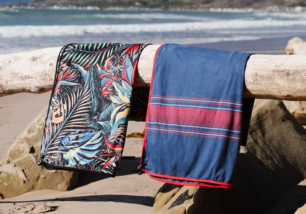 Two beach towels draped over a log