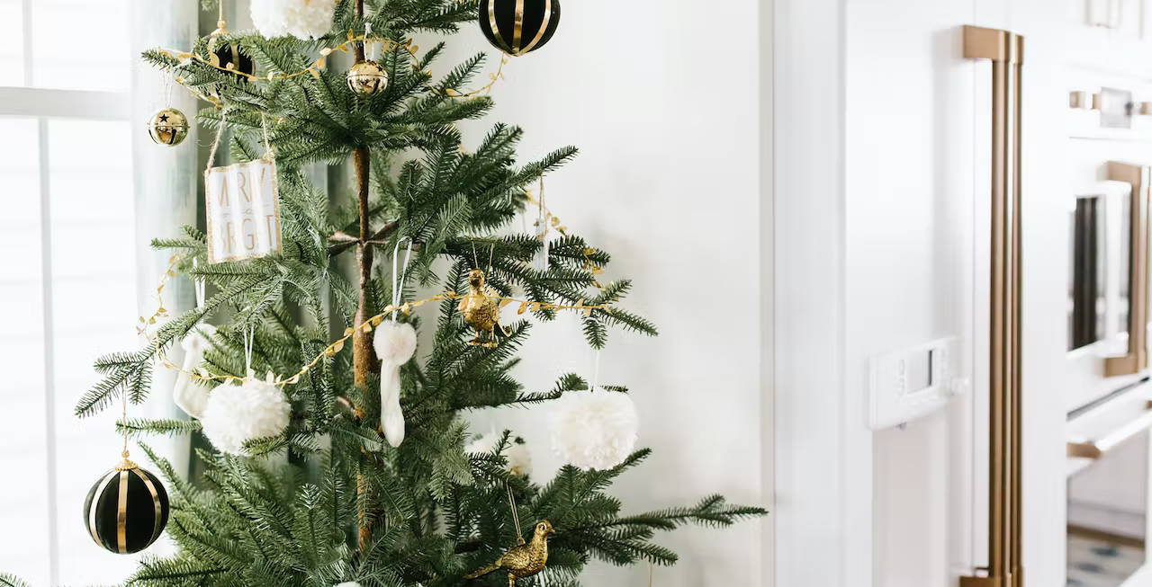 Christmas tree by refrigerator with gold accents
