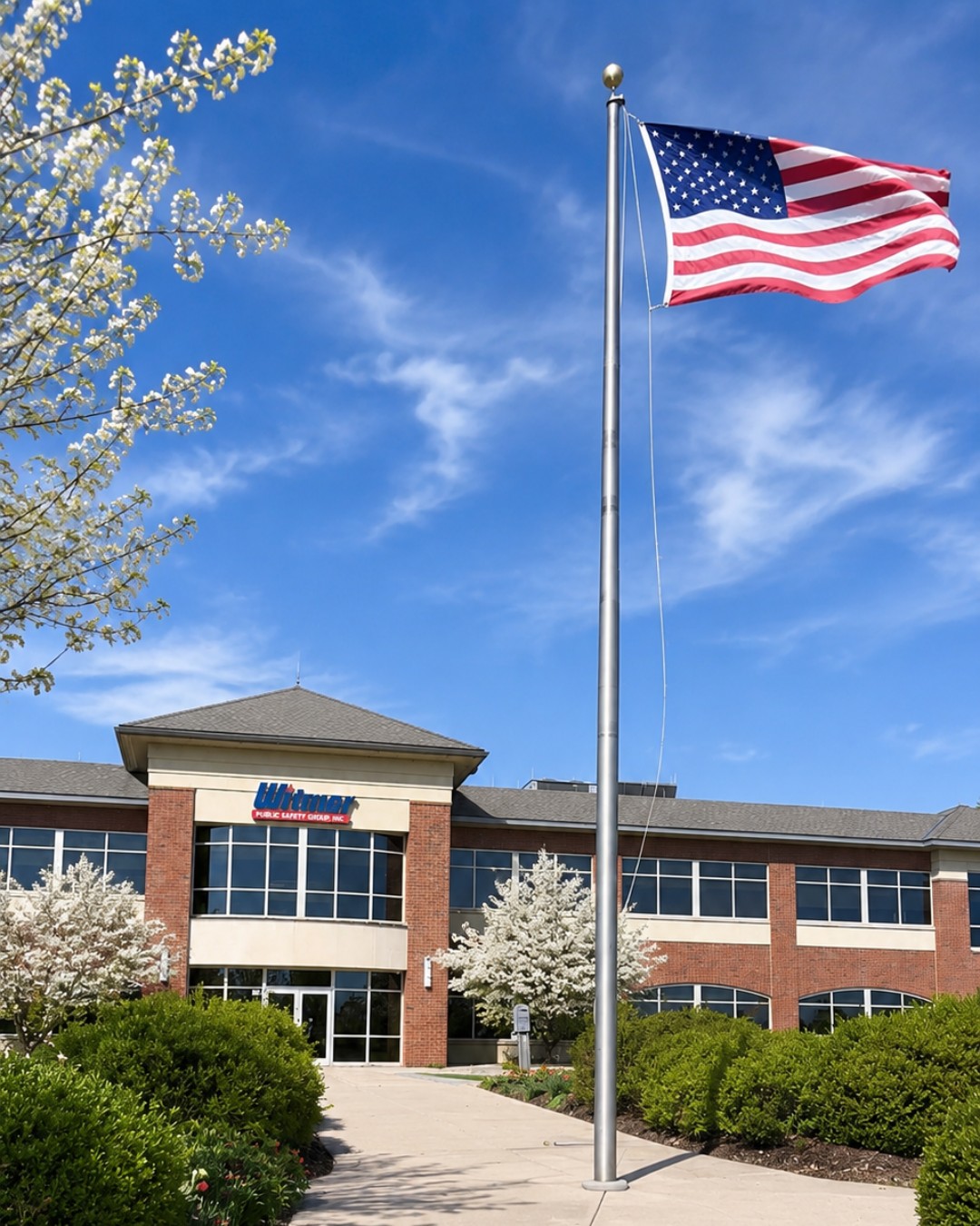 American flag waving in front of a brick building with blue sky.