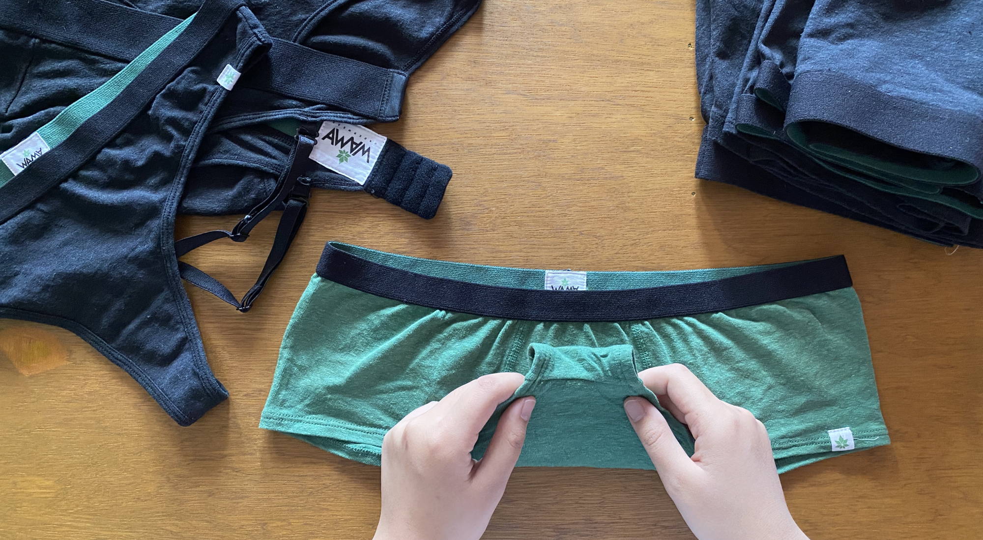 A person folding a pair of green WAMA boy shorts underwear to learn how to organize underwear.