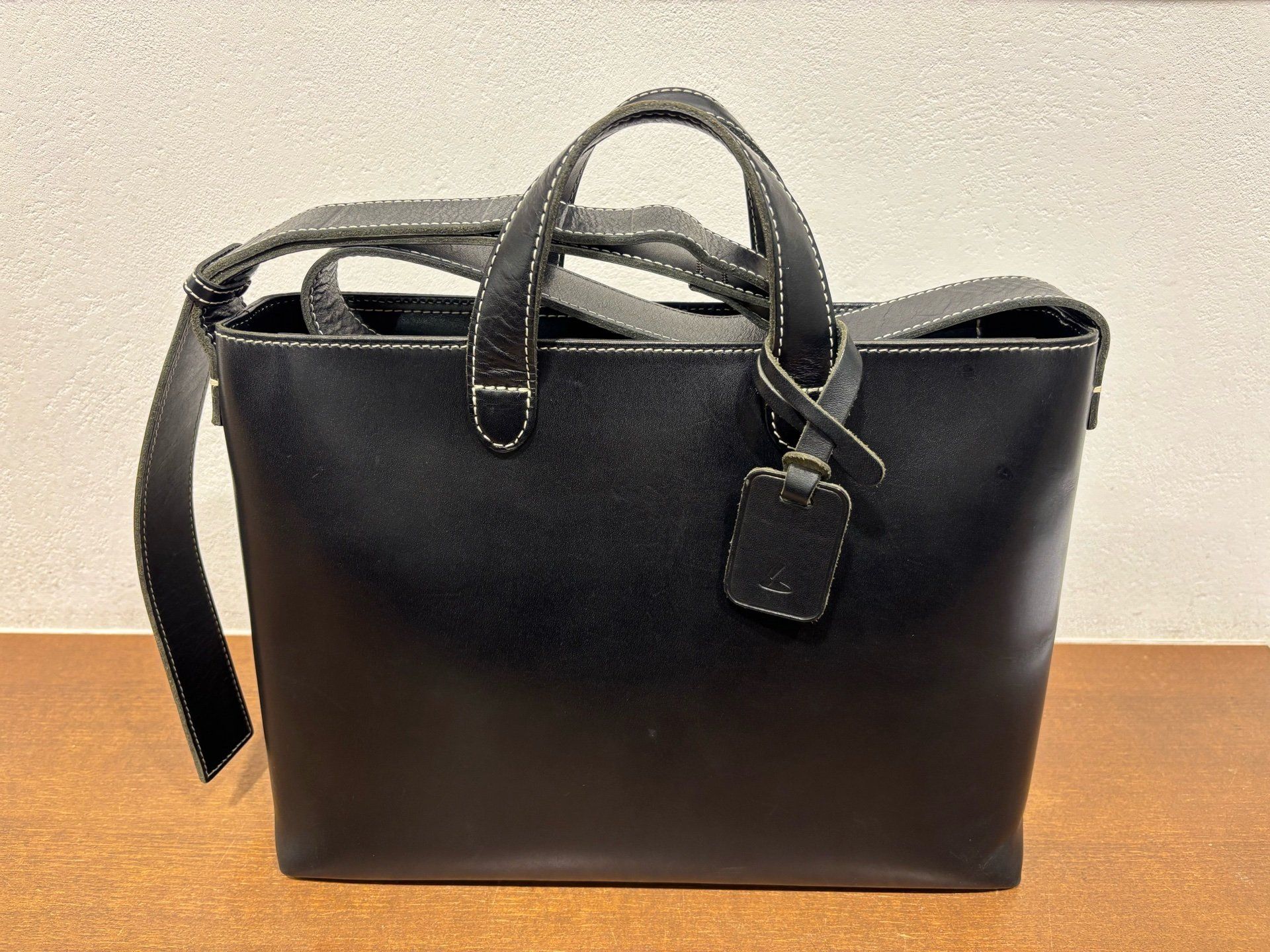 A black leather tote bag with handles and a tag.