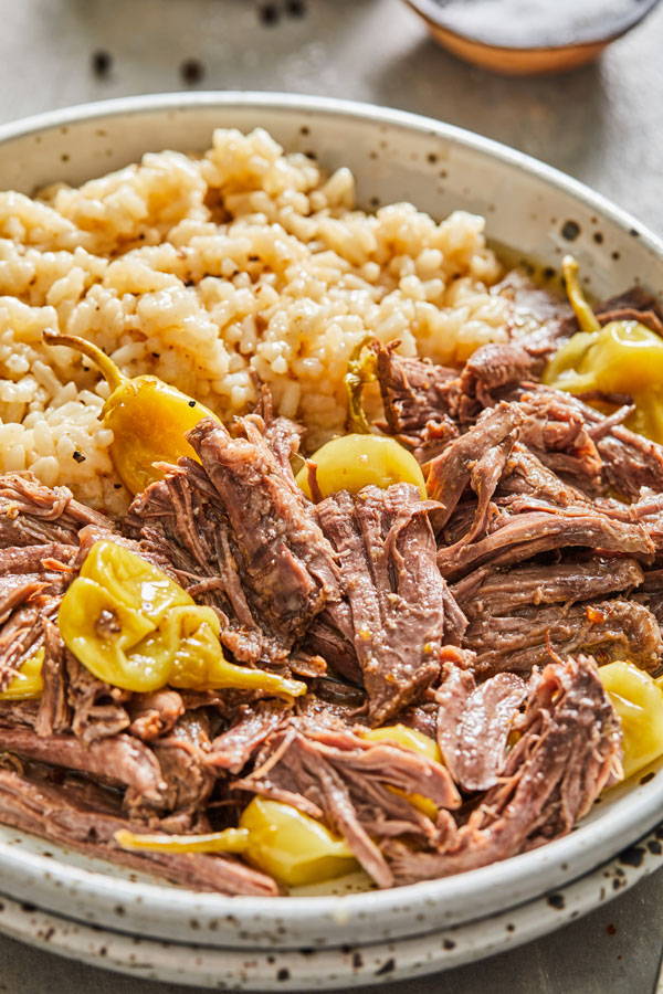Shredded pot roast with pepperoncini pepper served with rice in a bowl