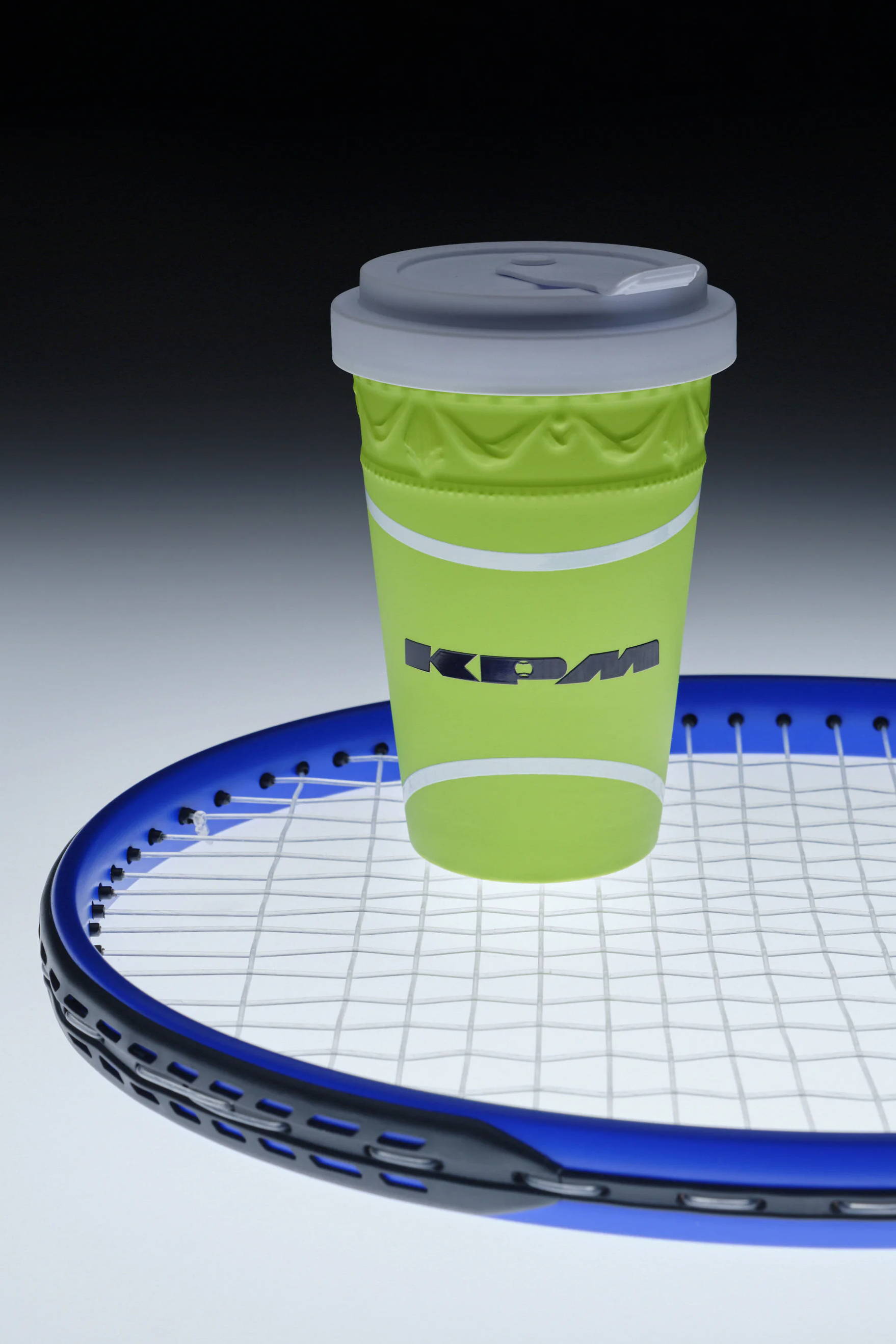 Green coffee cup on a blue tennis racket.