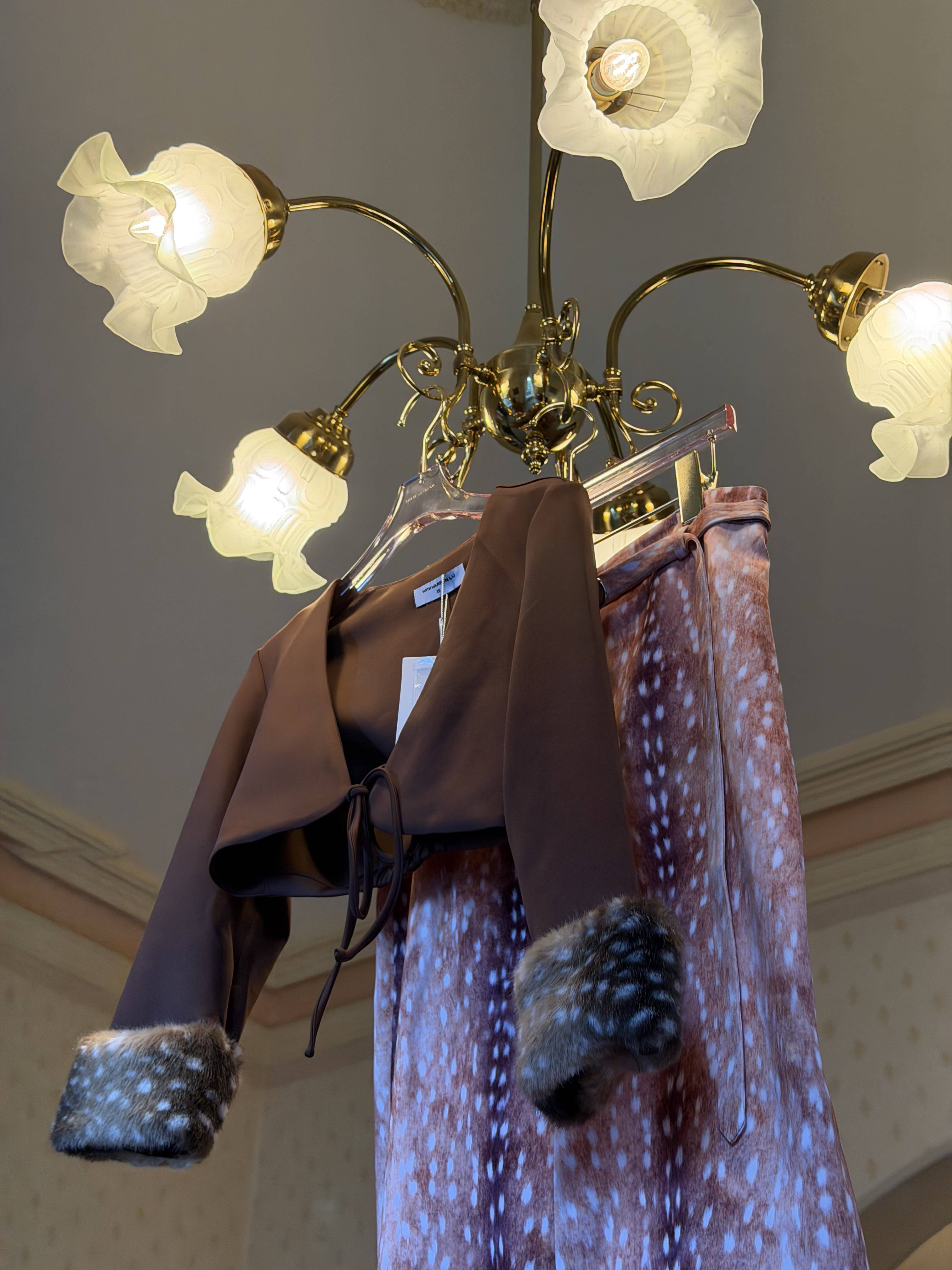 A brown top hanging near a chandelier with three light fixtures.