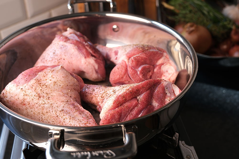 Lamb shank pieces in a 316 Series Low Casserole on a stove.