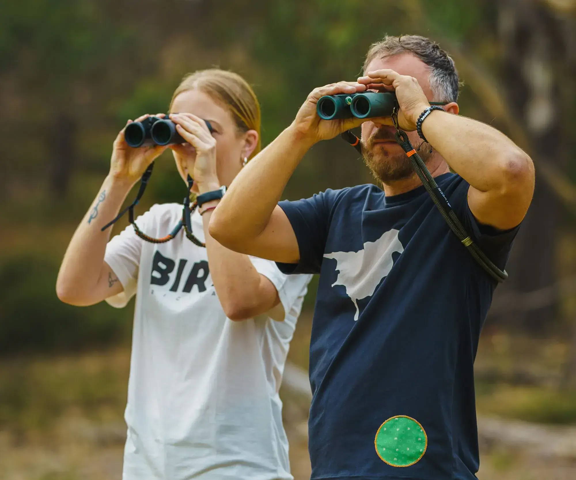 Male and Female bird-watching looking through binoculars in nature