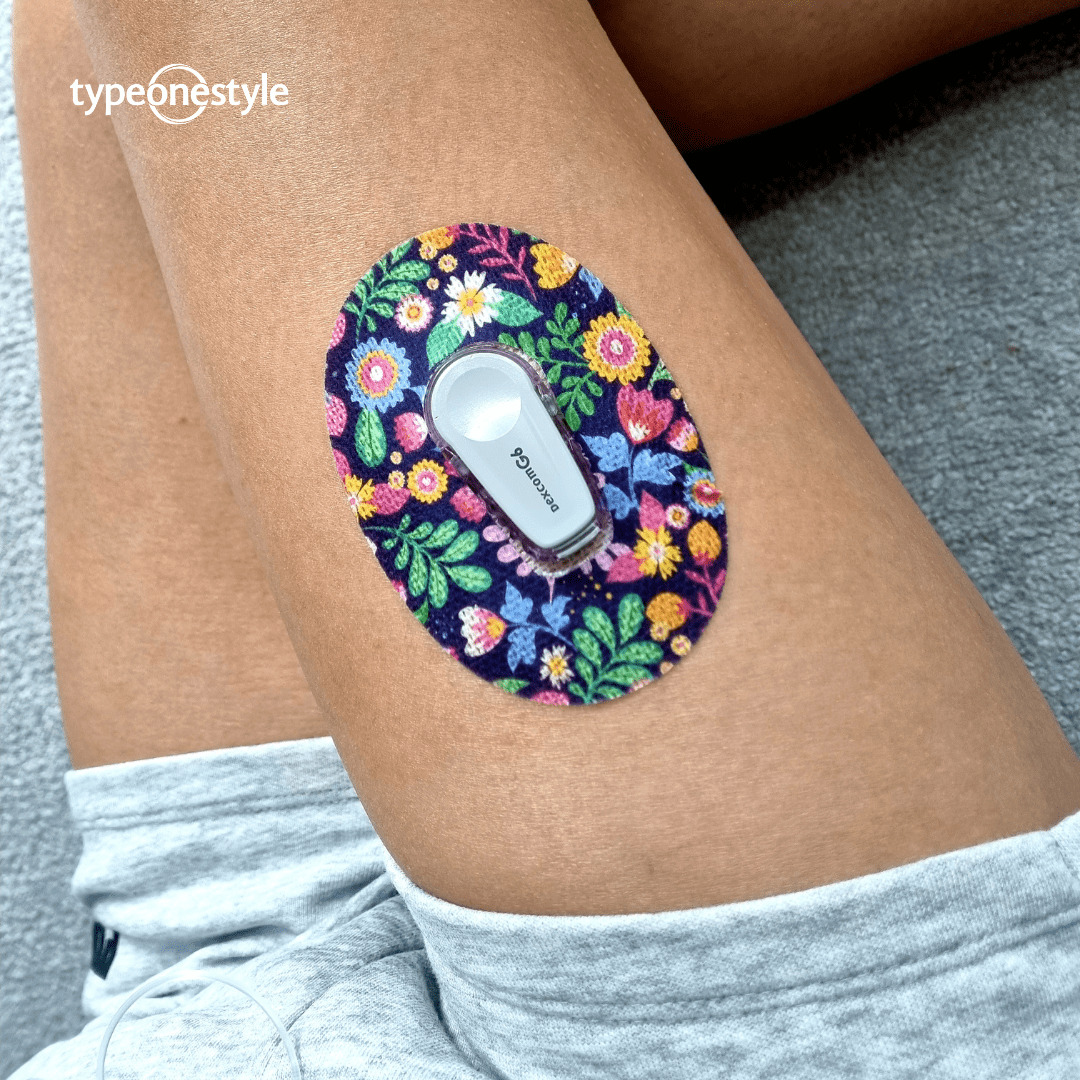 A person wearing a Vibrant Flowers CGM tape for her Dexcom G6 by Type One Style.