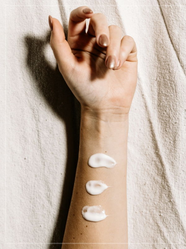 An arm visible from the elbow up, palm facing towards the camera, with three smears of makeup across the forearm. The arm is laying on a cloth.