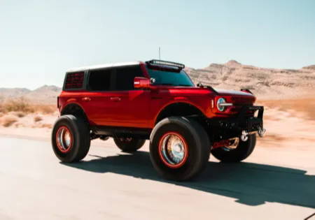 Lifestyle image of Ford Bronco driving down the highway in the desert.