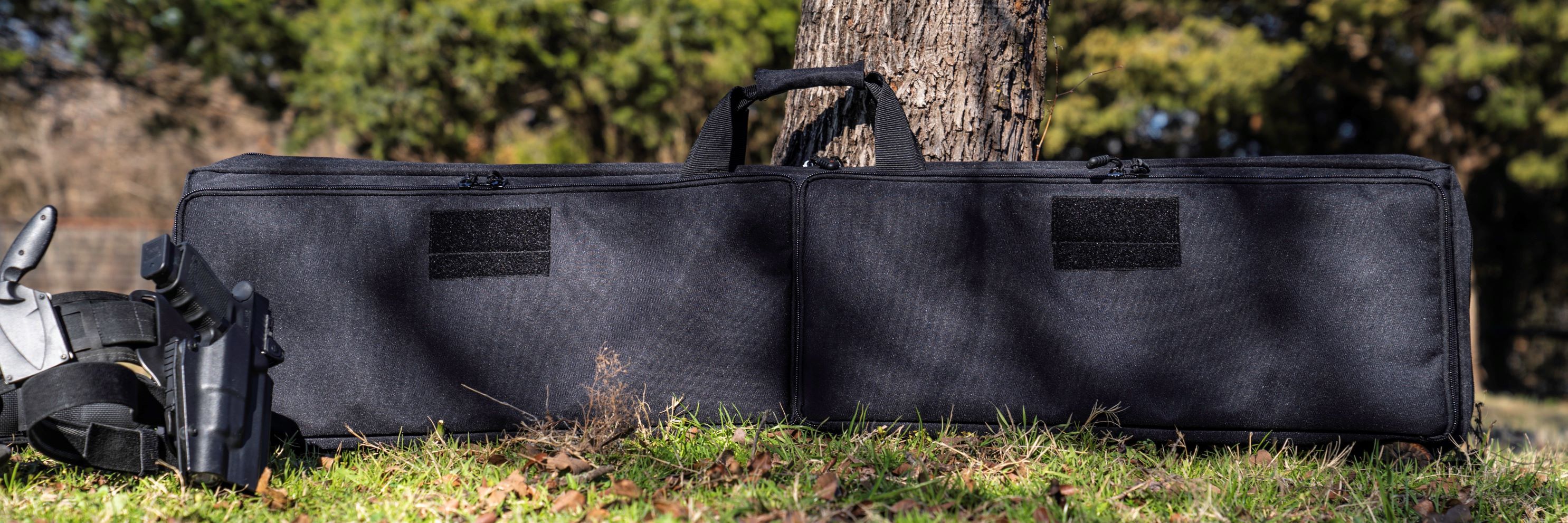 Black Single Rifle Case on ground in front of tree.