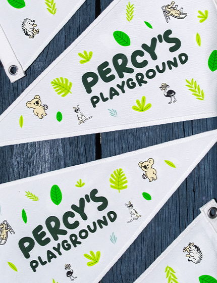 White triangular pennant flags printed with the Percy's Playground logo surrounded by illustrated animals and tropical leaves