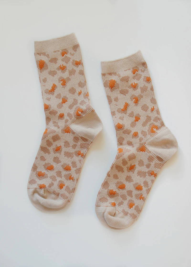 A pair of oatmeal, pink and orange crew socks with a leopard print pattern