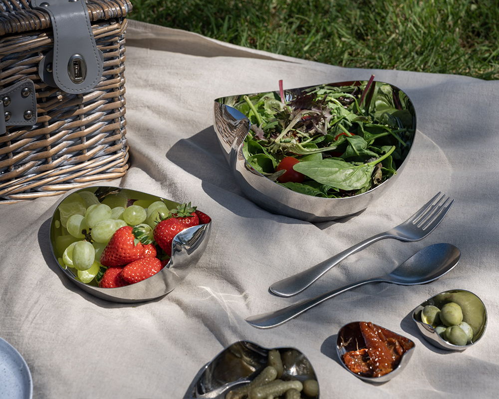 A picnic setup with salad, fruits, and Quinton Vintage cutlery on a blanket.