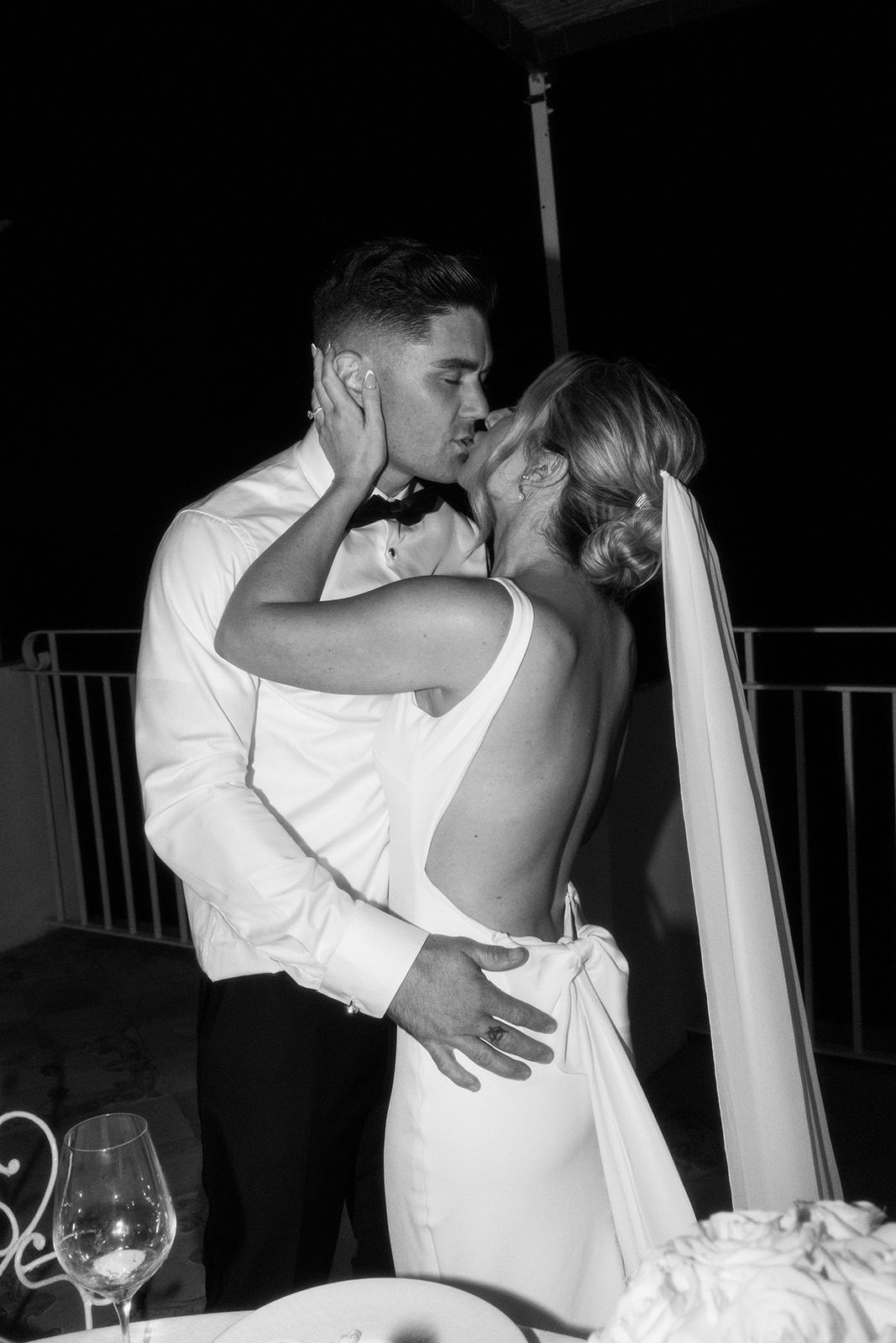 A couple sharing a romantic kiss at a wedding reception.