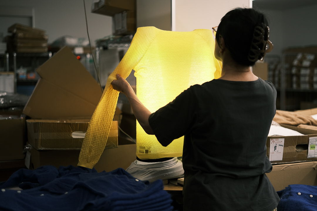 Person holding a yellow shirt in a warehouse setting.