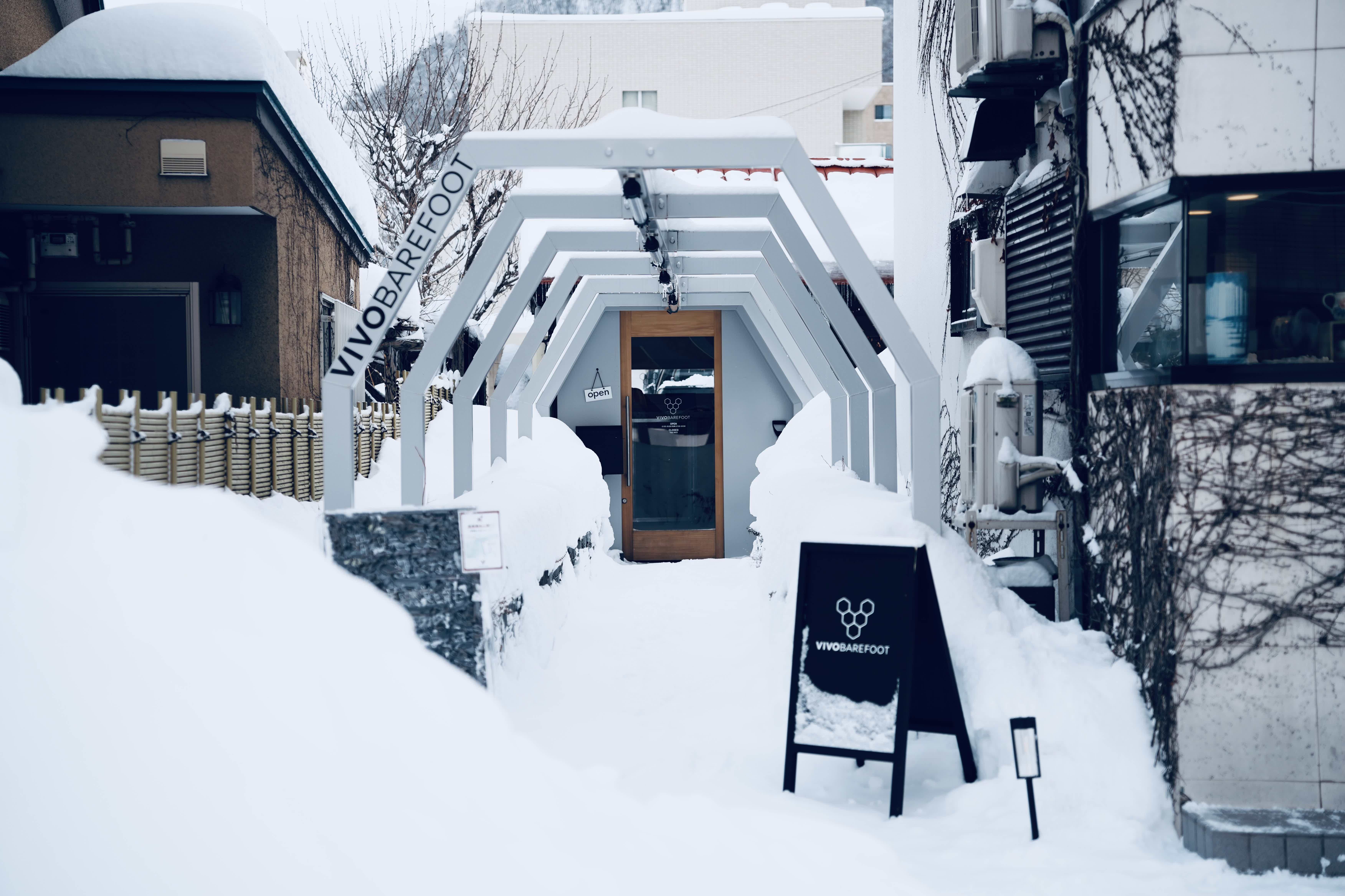 Snow-covered entrance with a sign and modern architecture.