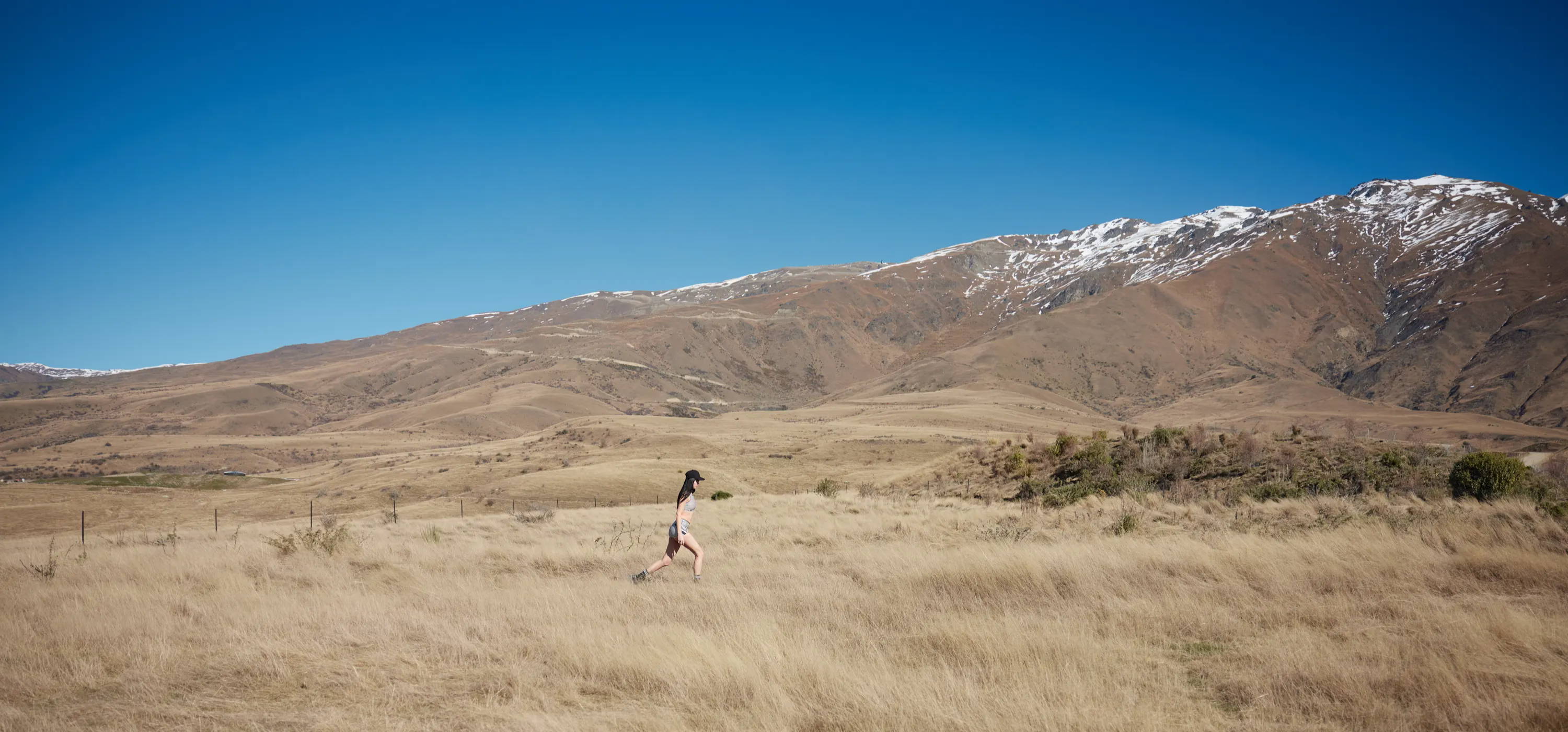 Girl walking through the wilderness, with snow-capped peaks in the background