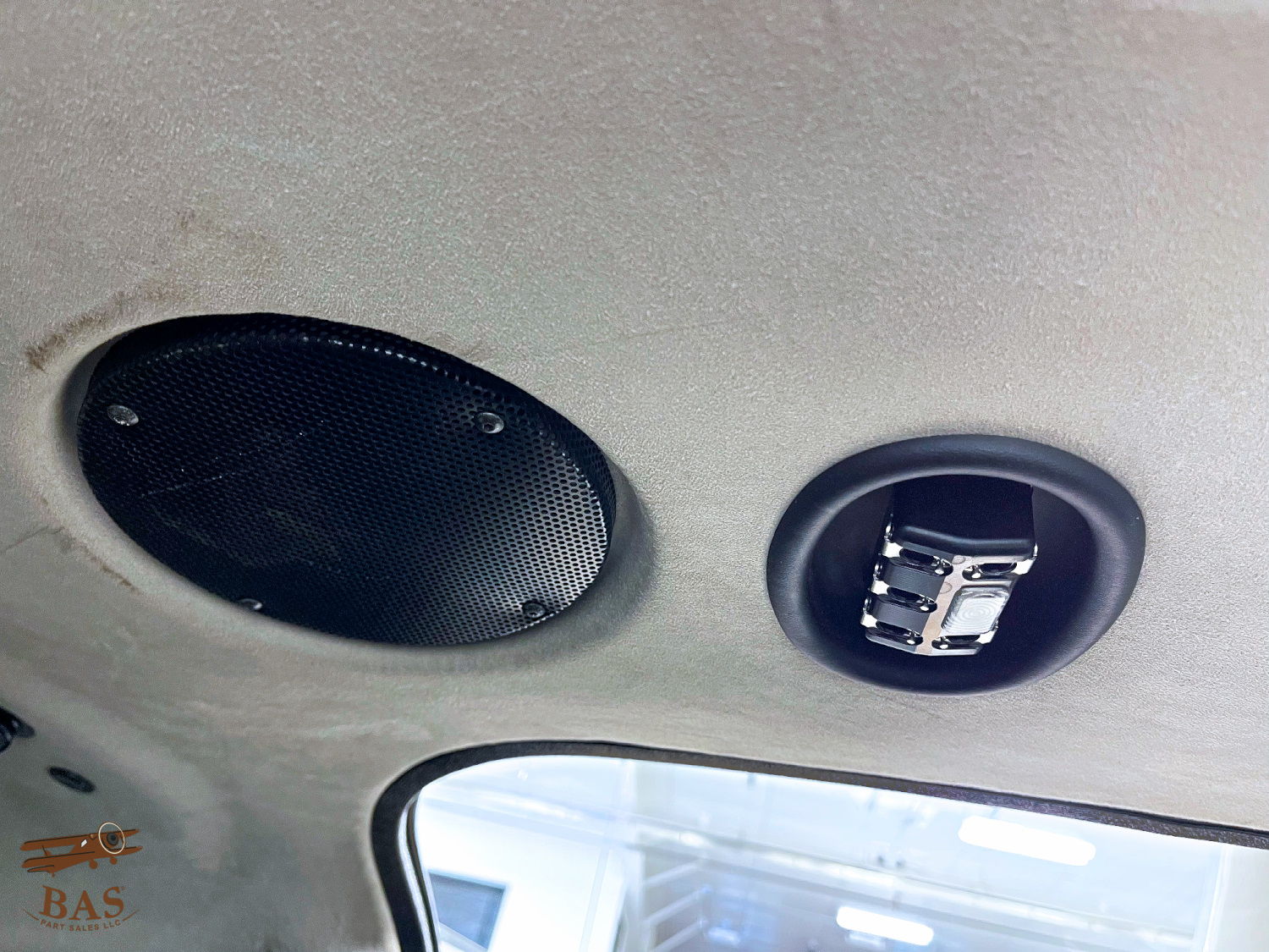 Interior view of a car ceiling with two speaker installations.