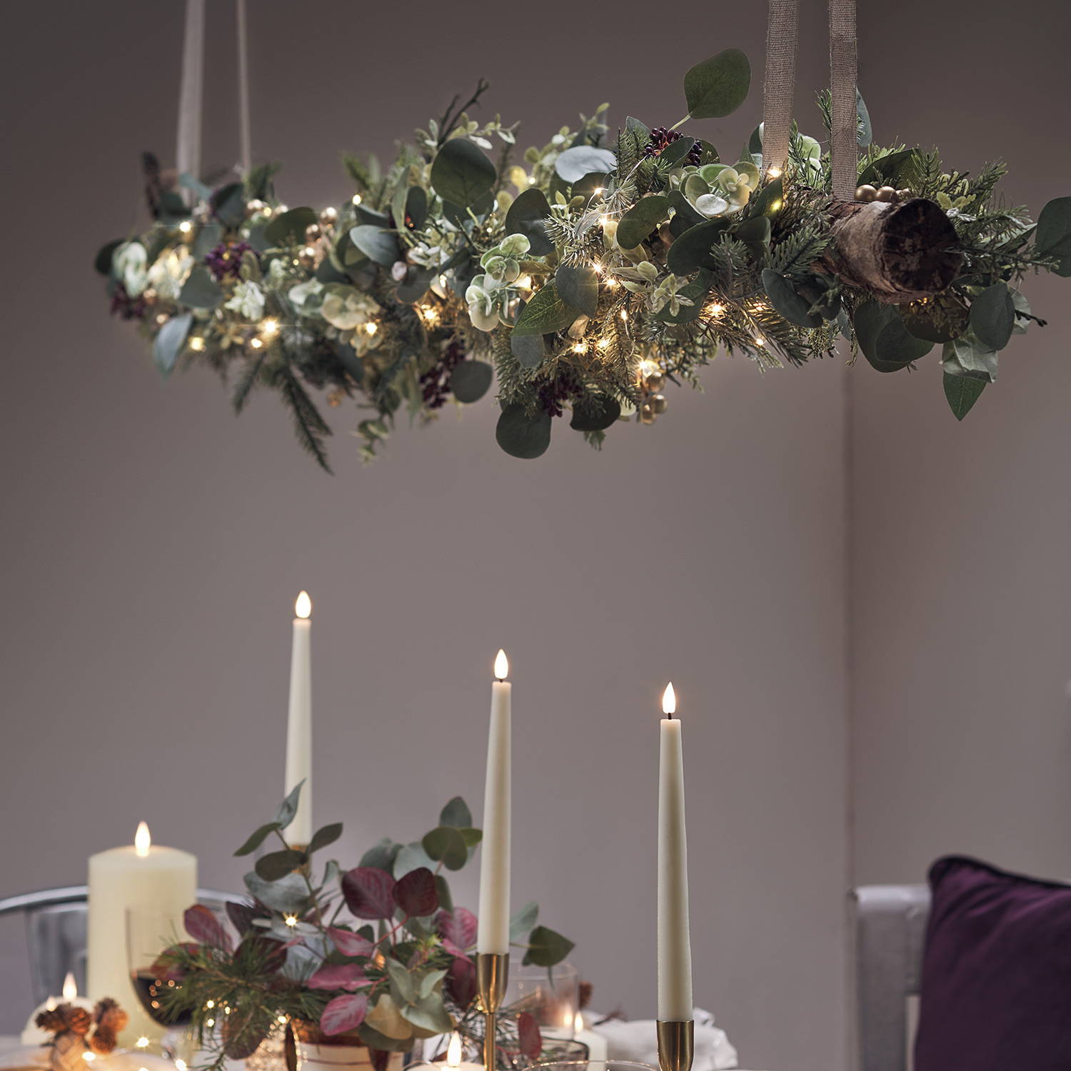 A DIY hanging Christmas decoration suspended above a Christmas dining room setup