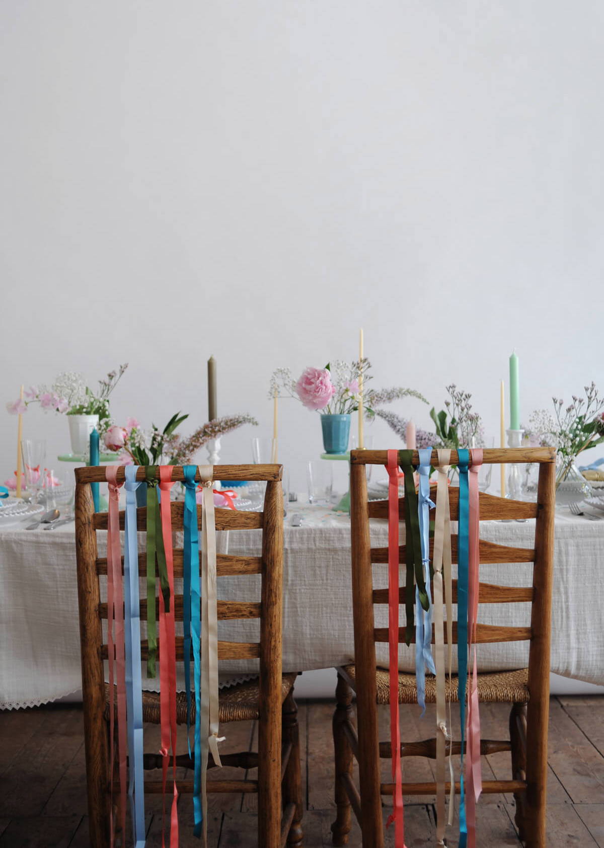 A photograph of ribbon-adorned chairs set at the wedding tablescape.