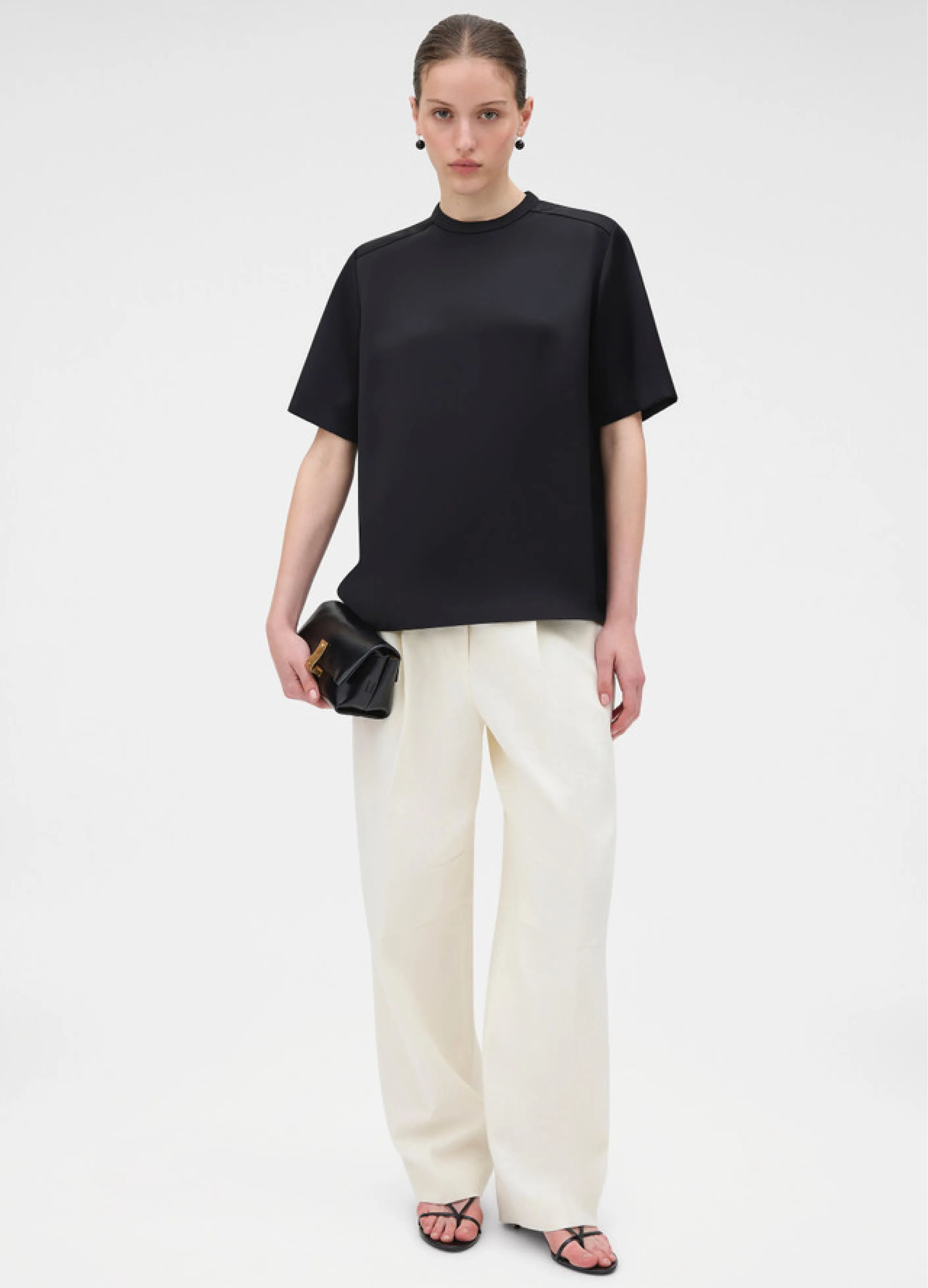 A model wearing a black top and white wide-leg pants.