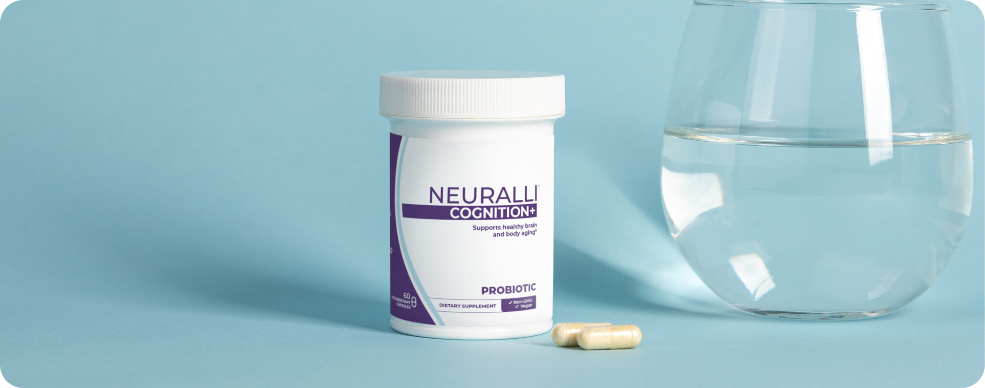 Container of supplements next to a glass of water on a blue background.