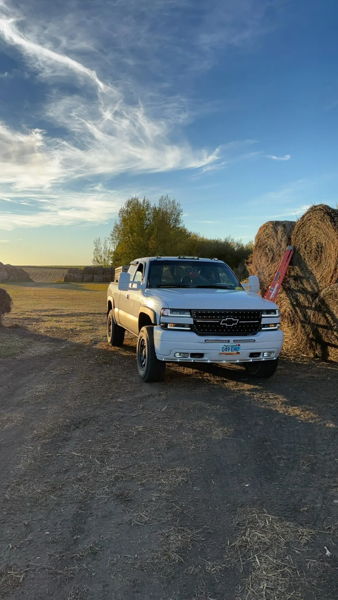 Front three-quarter view of James' white 2001 Chevy Silverado 2500HD parked near hay bales at sunset, install photo 5