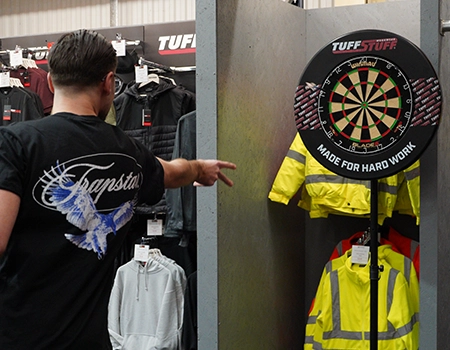 Person pointing at a dartboard near yellow jackets on display.
