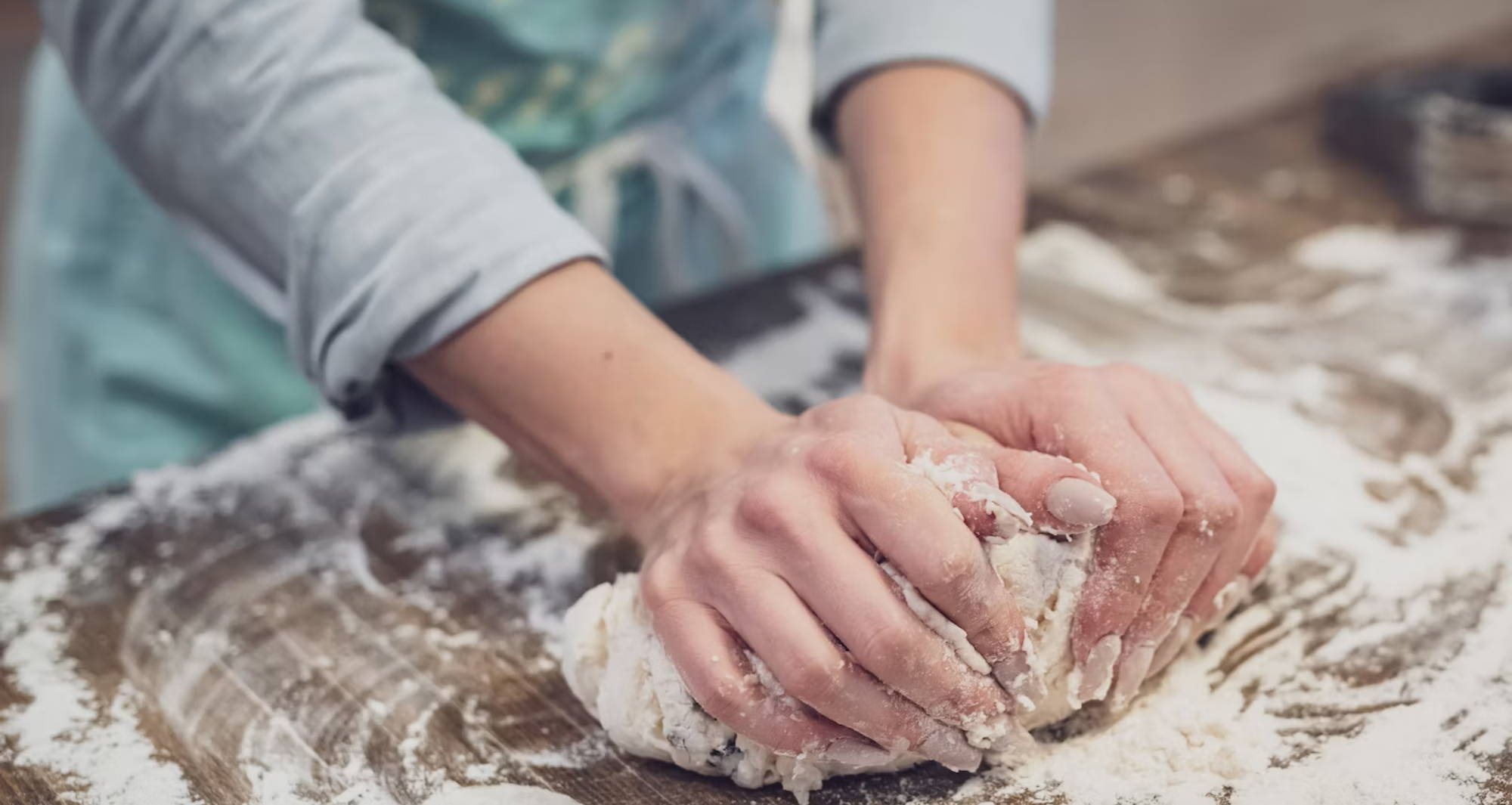 two hands rolling out dough with lots of flour surrounding
