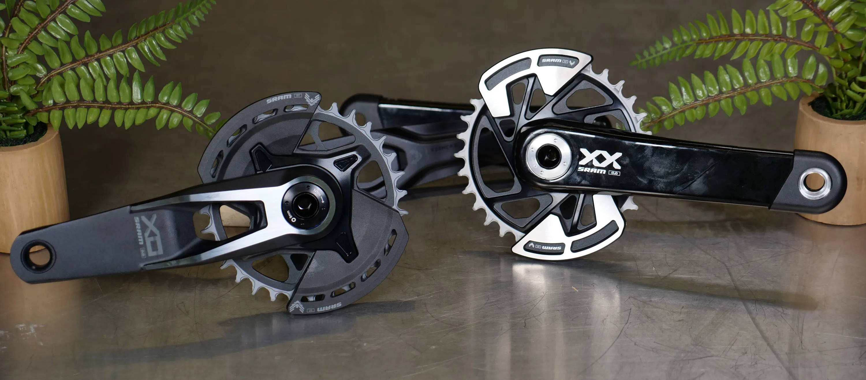 sram x0 and xx axs transmission cranksets on a table with ferns