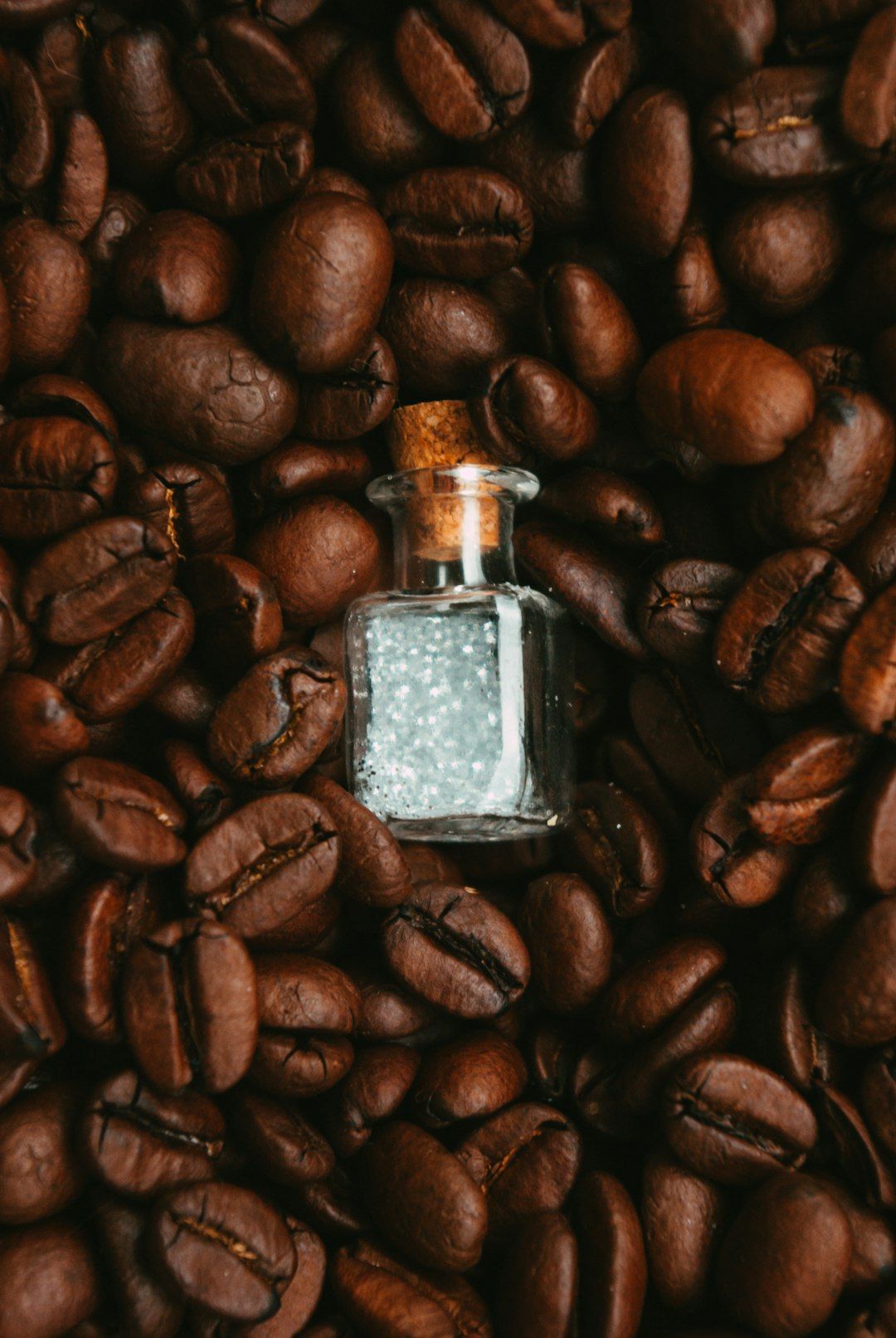 a small bottle sitting on top of a pile of coffee beans