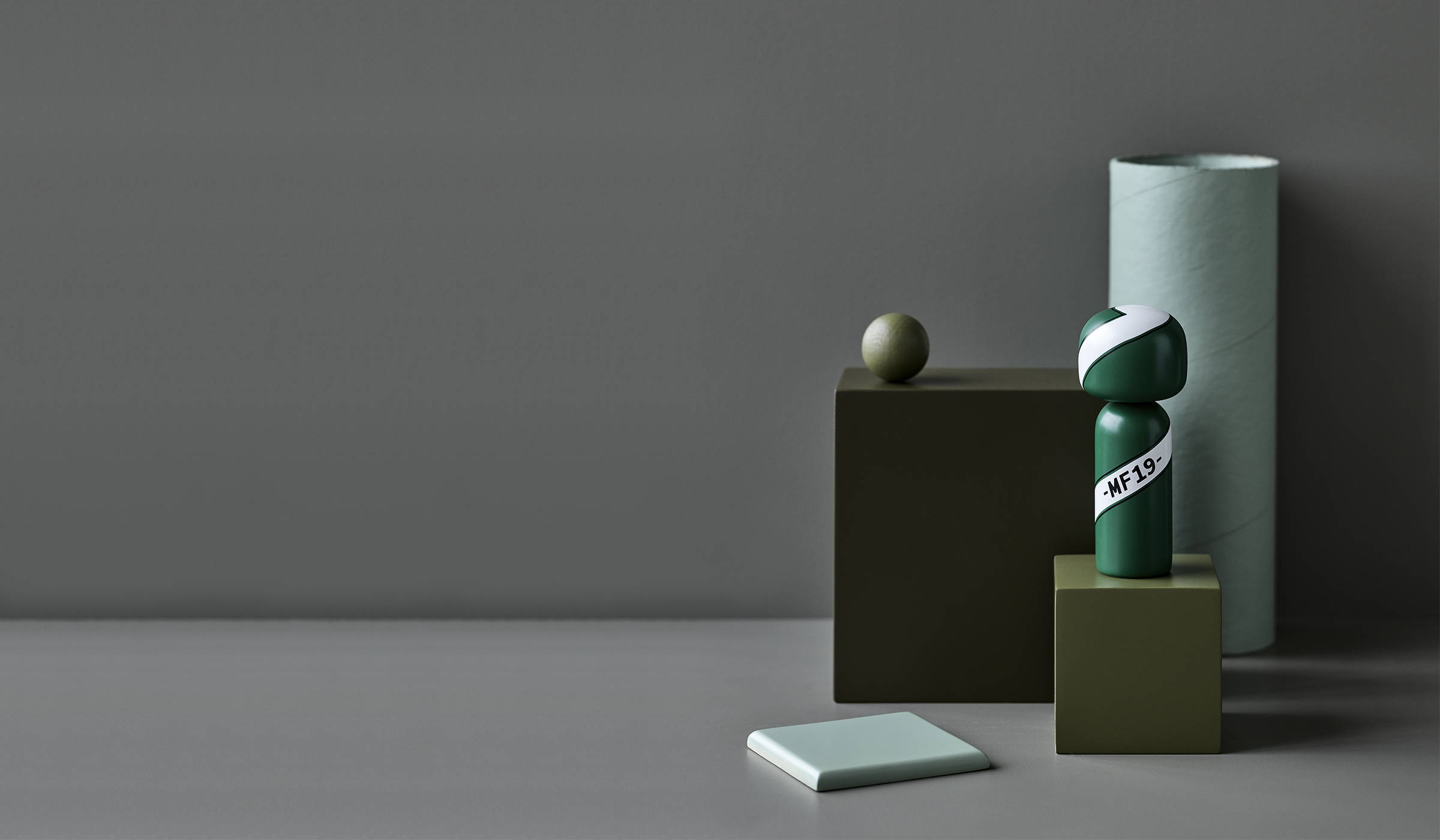 Three green vases next to a collectible Kokeshi doll