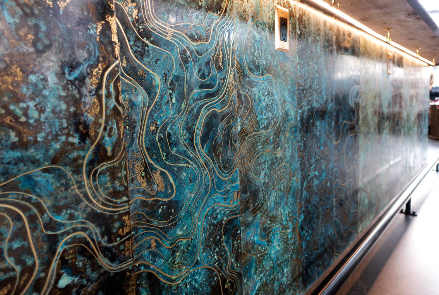 A large, abstract, blue and gold mural on a wall. 