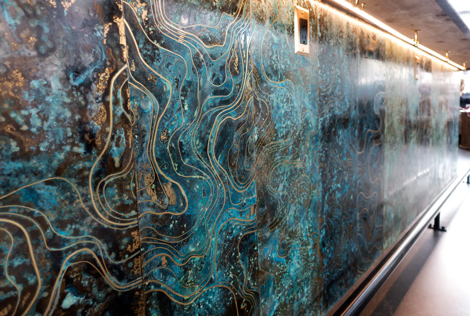 A large, abstract, blue and gold mural on a wall. 