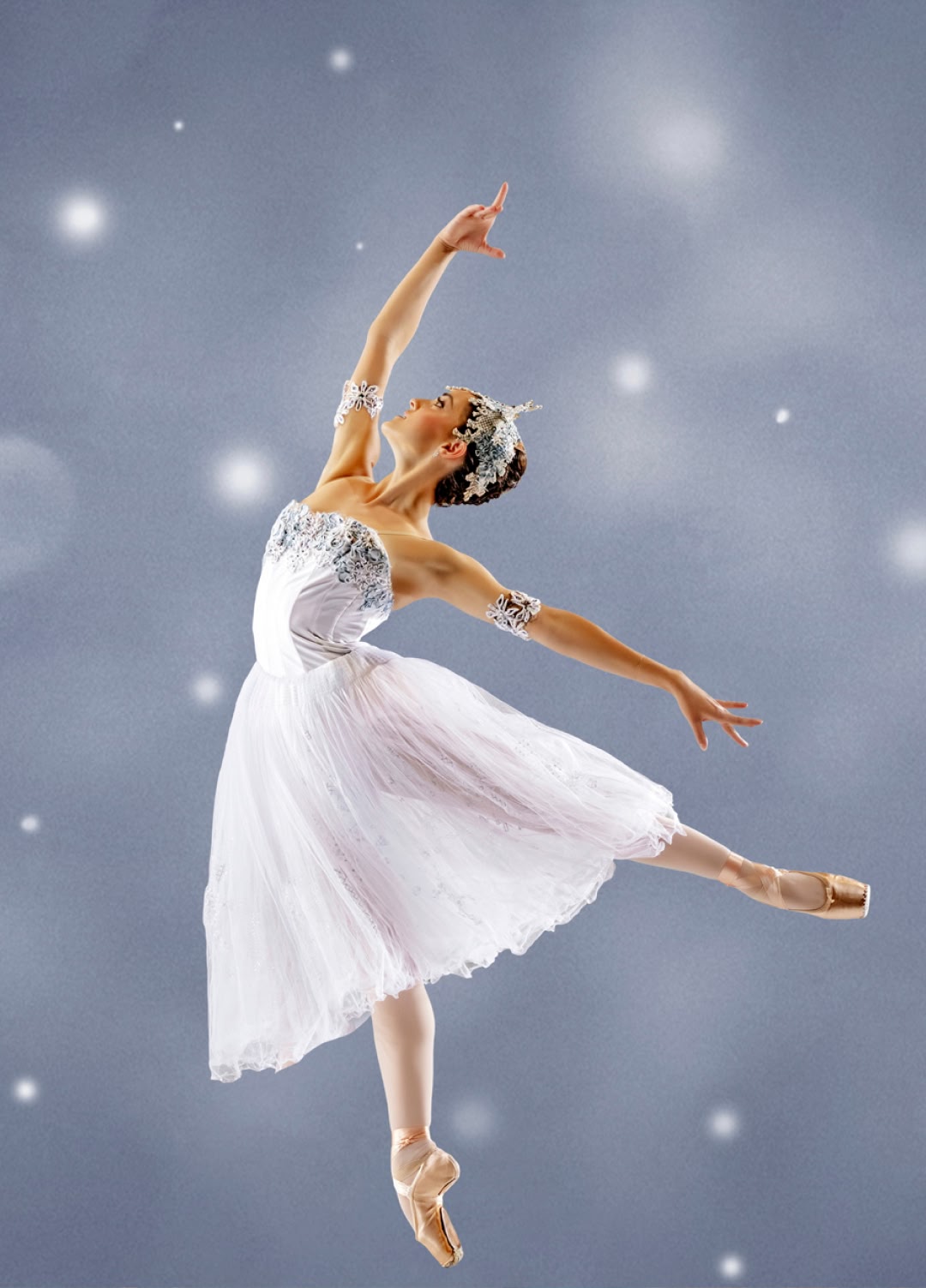 Ballet dancer in white dress performing against a soft, blurred background.
