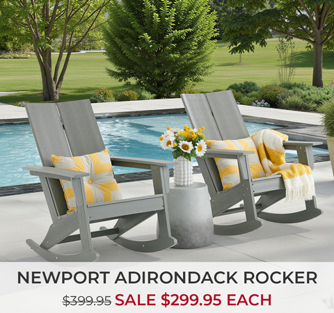 Two gray Adirondack rockers by a pool with decorative pillows and flowers.