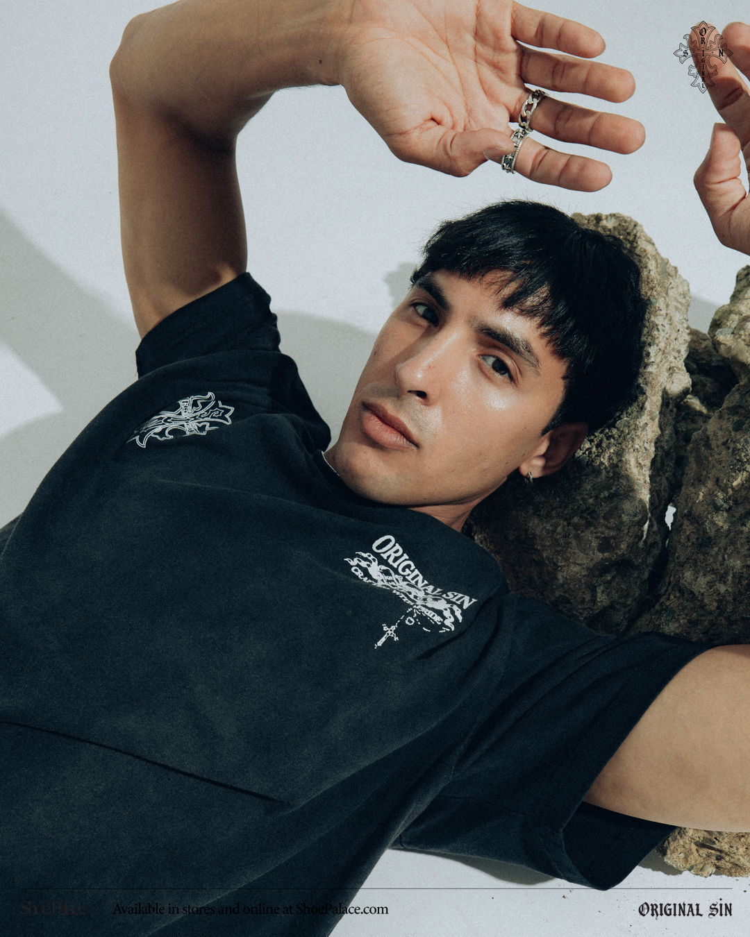 A person lying down with hands raised, wearing a black shirt.