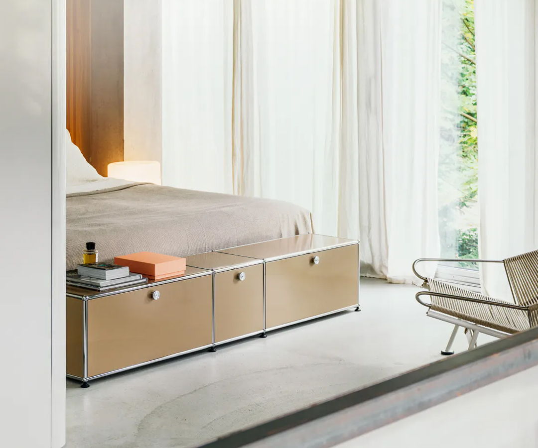 A modern bedroom featuring a bed, USM Haller storage unit, and chair.