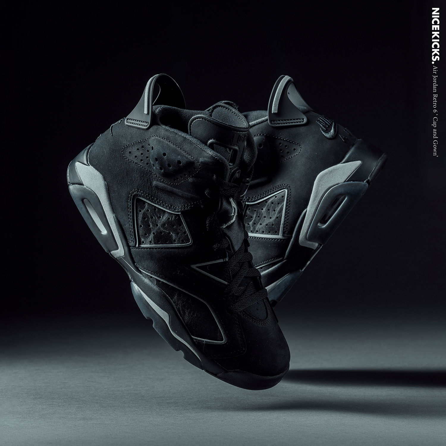 Black sneakers displayed in mid-air against a dark background.