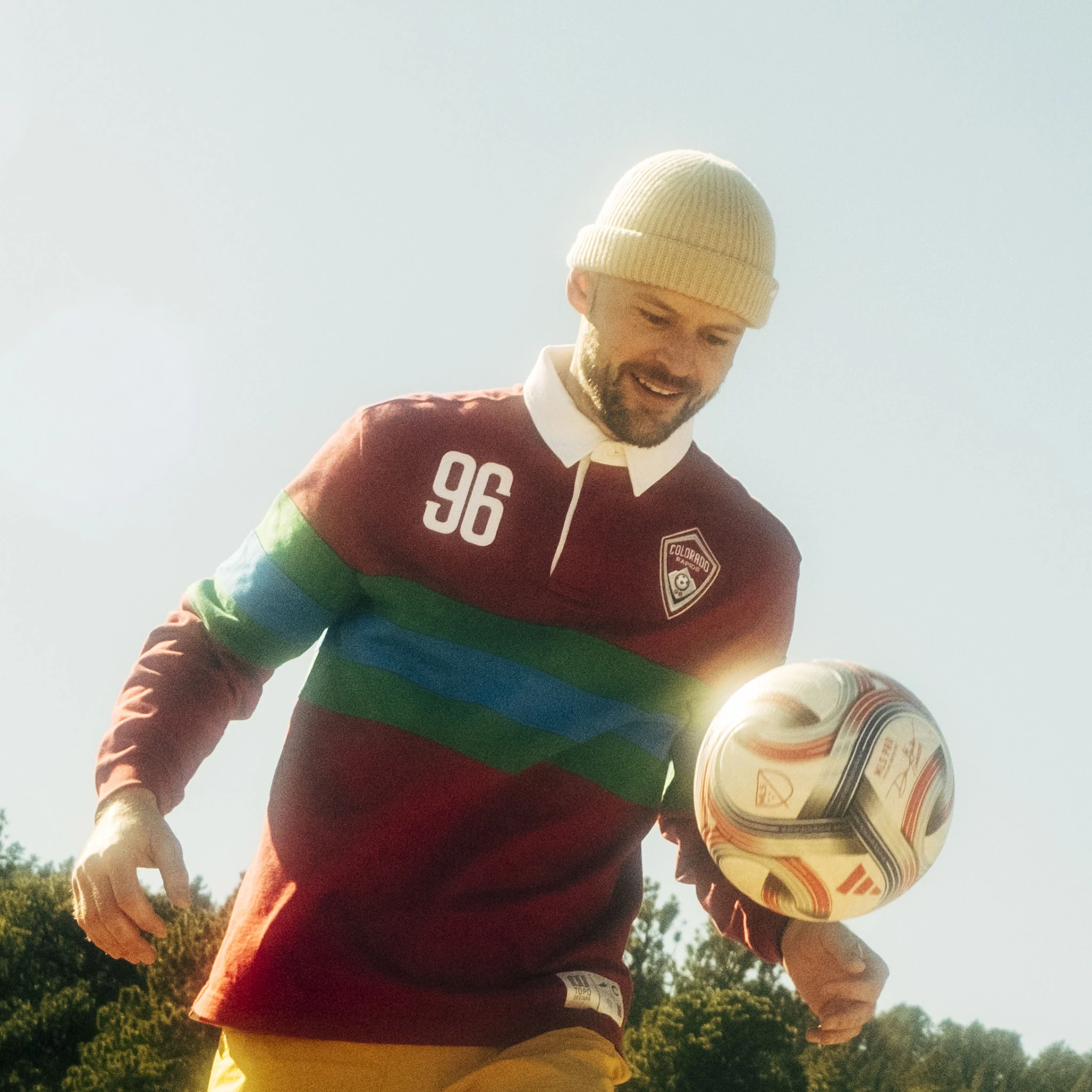 Person in a colorful sweater playing with a soccer ball outdoors.