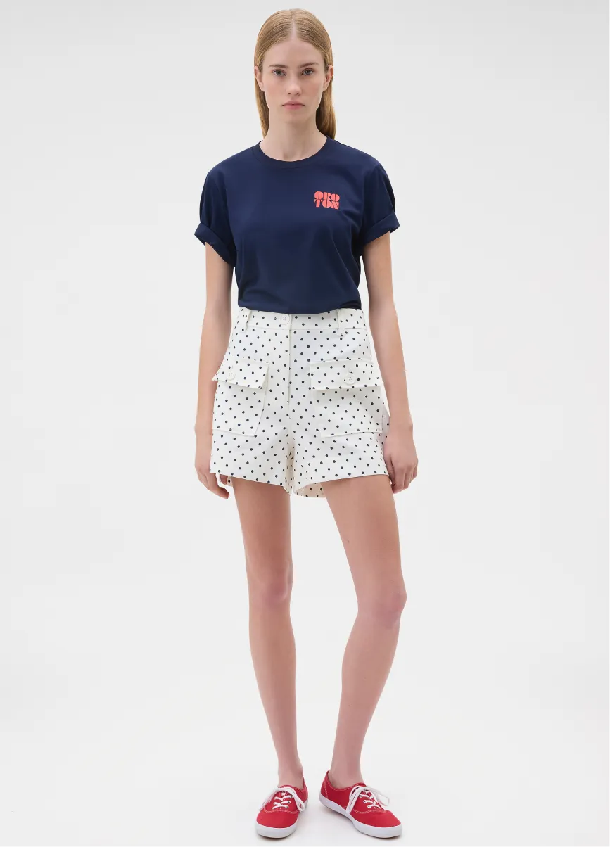 A young woman wearing a navy t-shirt and polka dot shorts.