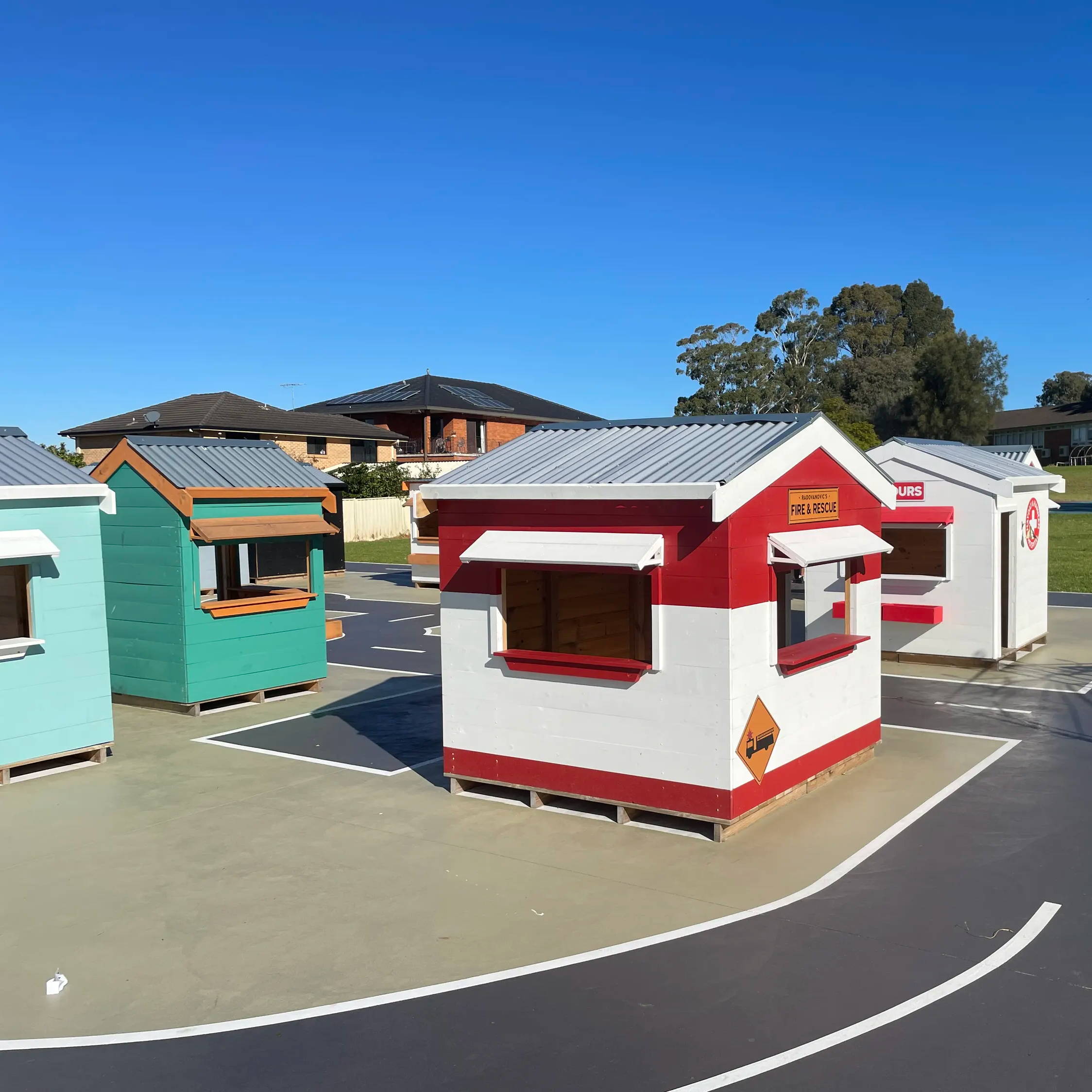 A cubby House village with a fire station, hospital, and drive through cubby house.