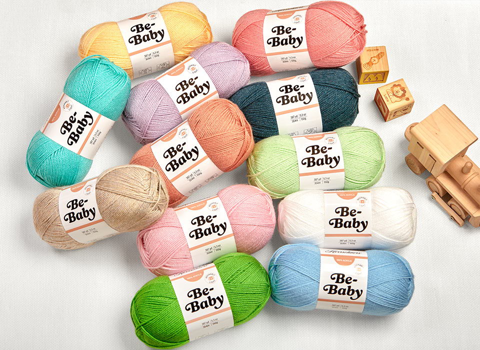 Colorful yarn skeins arranged with wooden blocks on a light background.