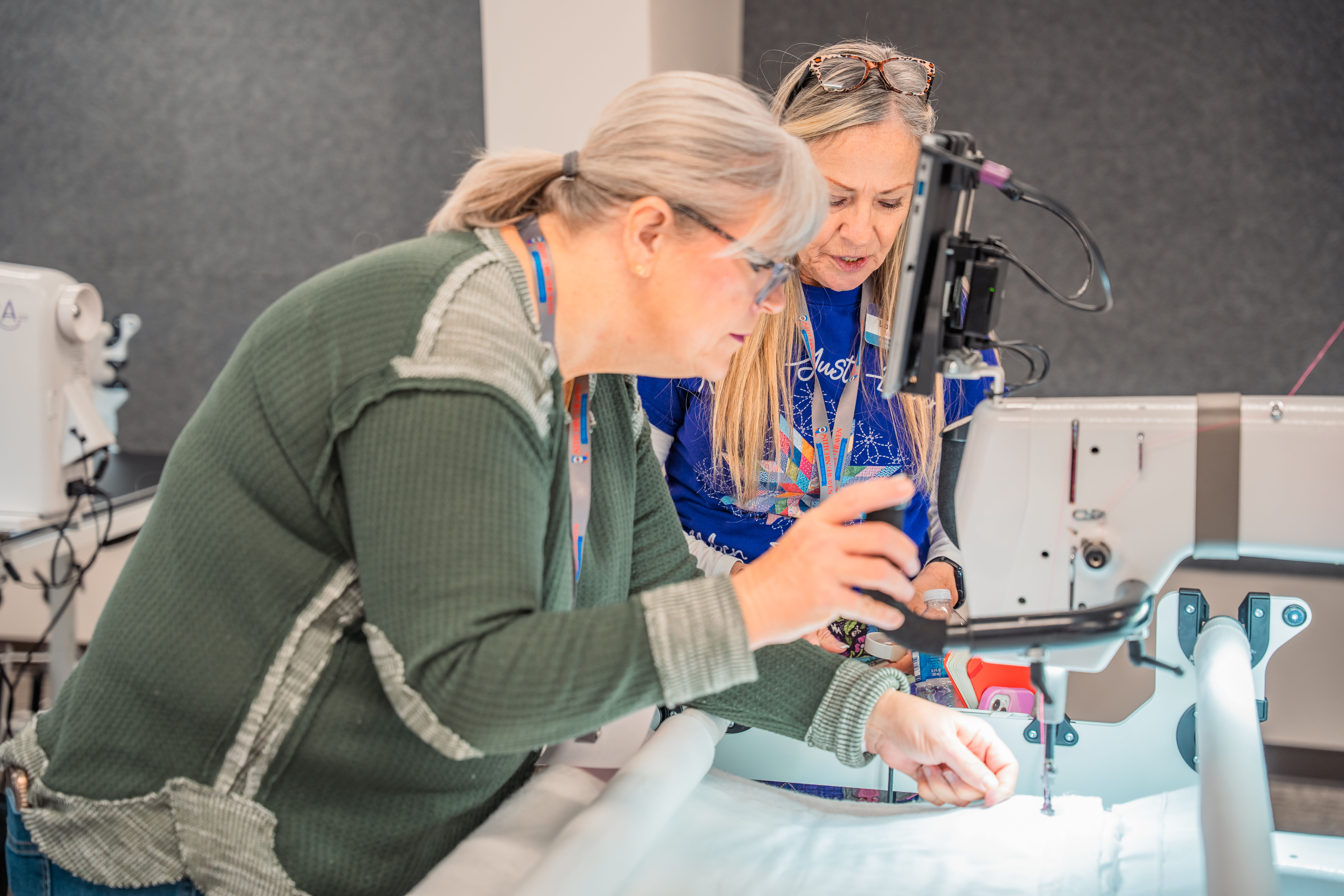 Two women working together on a sewing machine in a workshop.