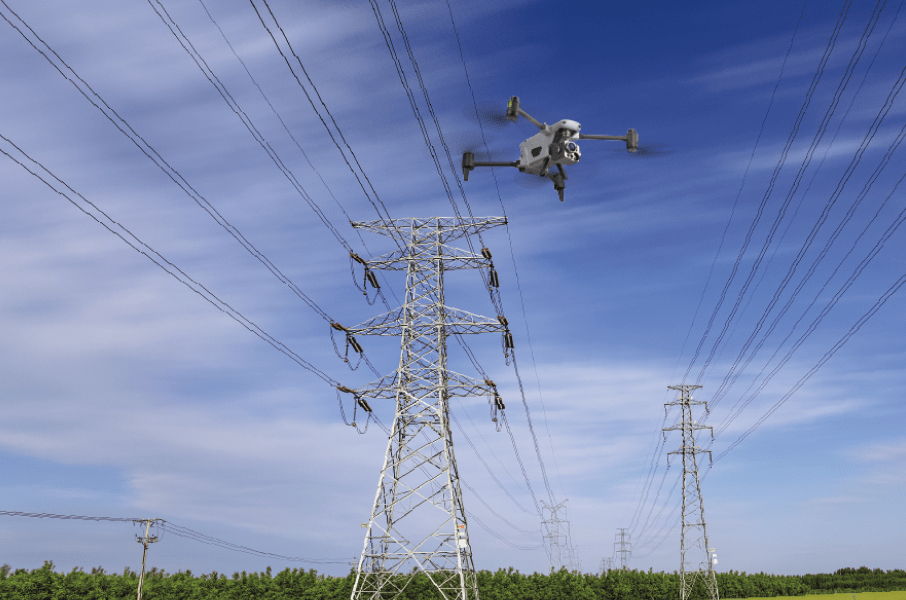 An Autel Alpha drone flying near high voltage power lines under a blue sky.